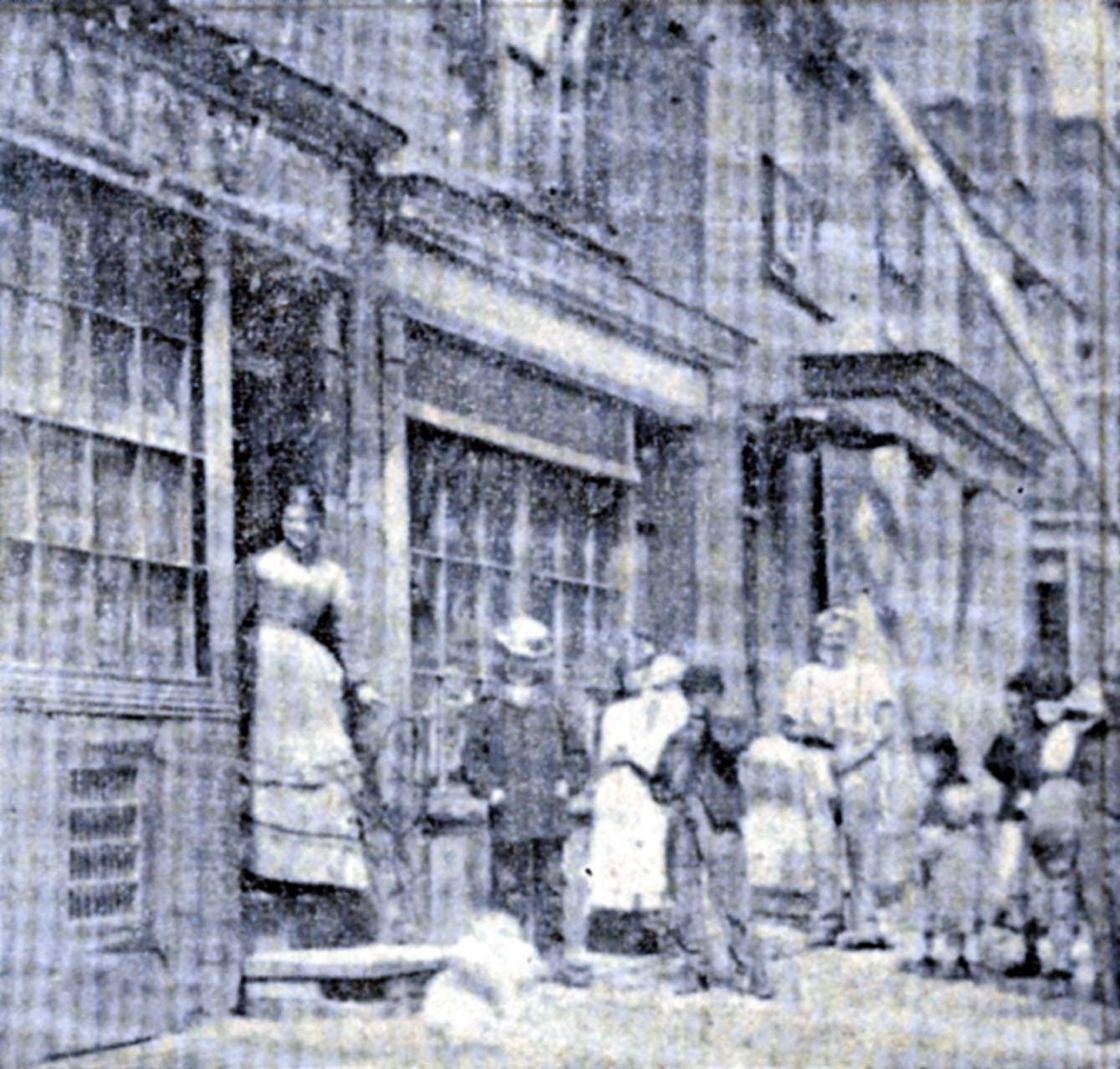 Group of people stood outside of a store with one in the doorway.